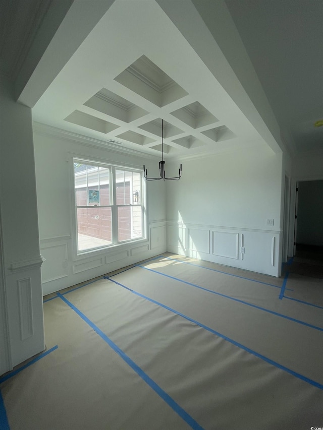 unfurnished room with a decorative wall, coffered ceiling, a chandelier, beamed ceiling, and a wainscoted wall