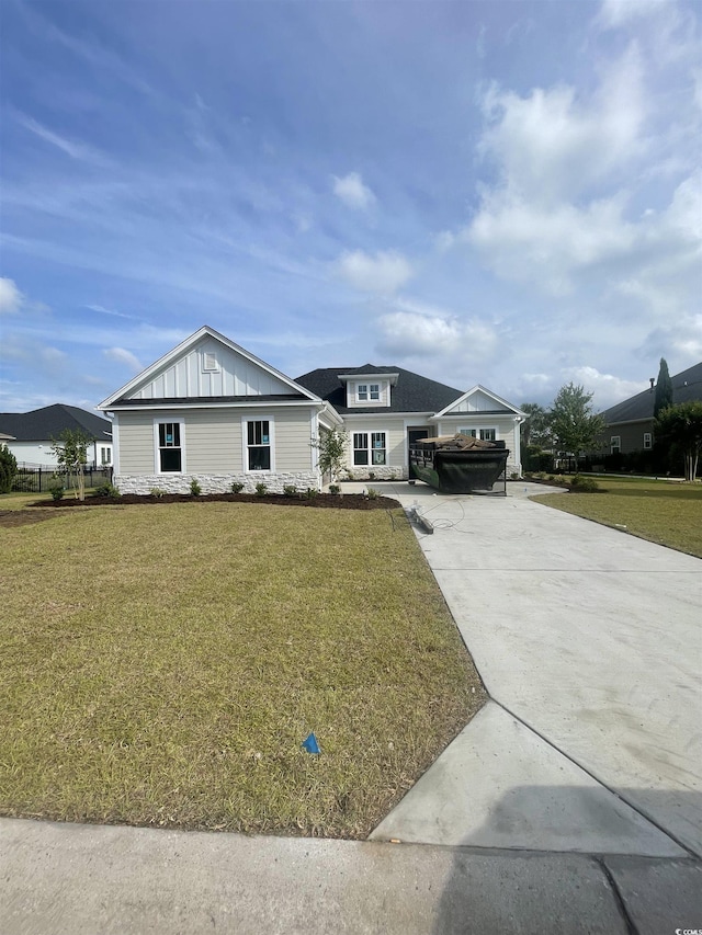 view of front of property featuring concrete driveway, a front lawn, and board and batten siding