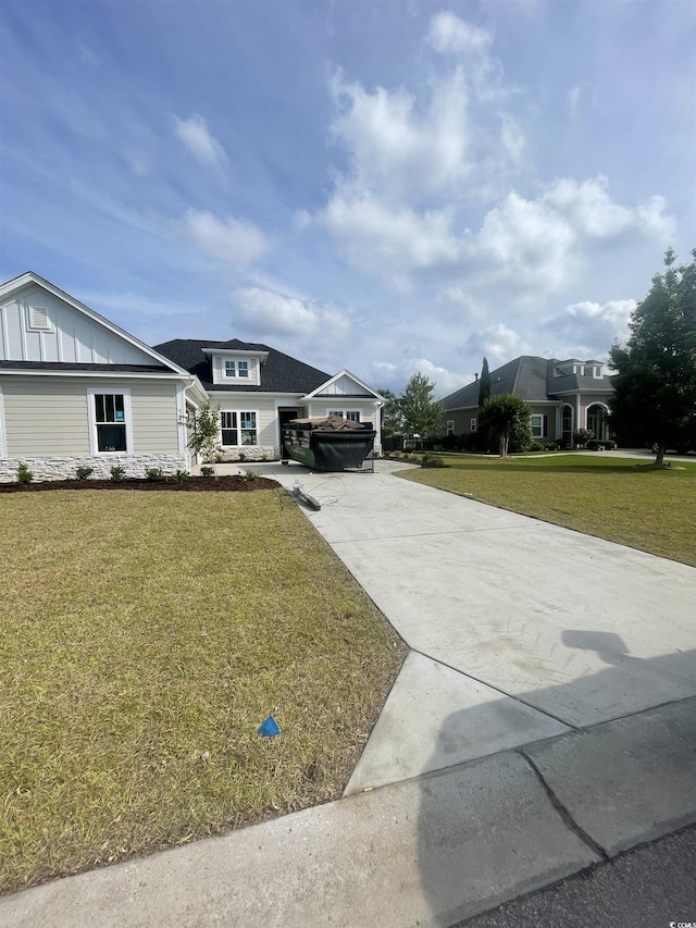 view of front facade with concrete driveway, a front lawn, and board and batten siding