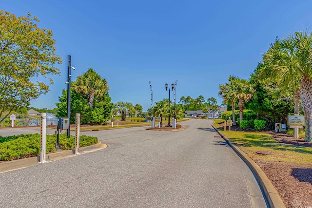 view of asphalt road featuring curbs and street lighting