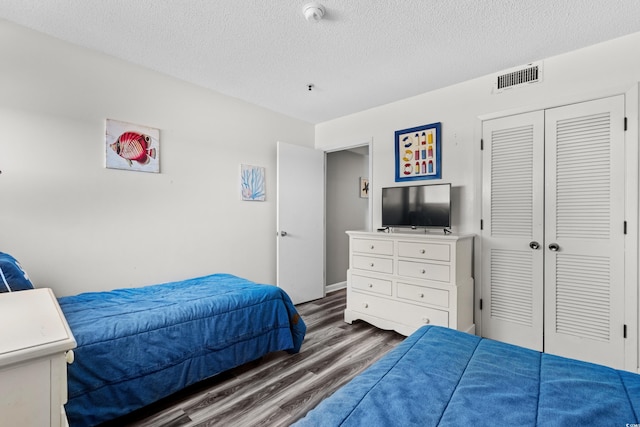 bedroom featuring a textured ceiling, a closet, and dark hardwood / wood-style flooring