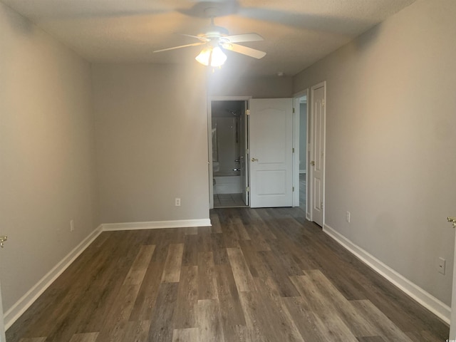 unfurnished bedroom with dark wood-type flooring, ceiling fan, and ensuite bath