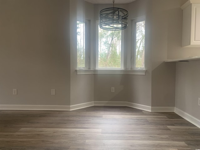 unfurnished dining area featuring a notable chandelier and wood-type flooring