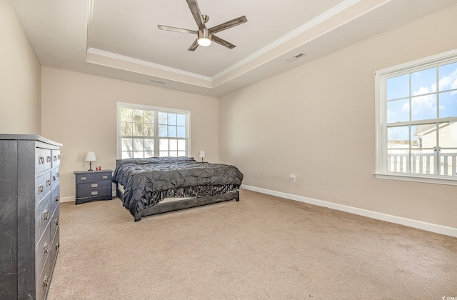 carpeted bedroom with ceiling fan, ornamental molding, a raised ceiling, and multiple windows