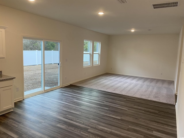 spare room with dark wood-style flooring, visible vents, and a healthy amount of sunlight