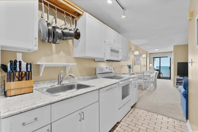 kitchen with white appliances, a textured ceiling, white cabinets, sink, and light colored carpet