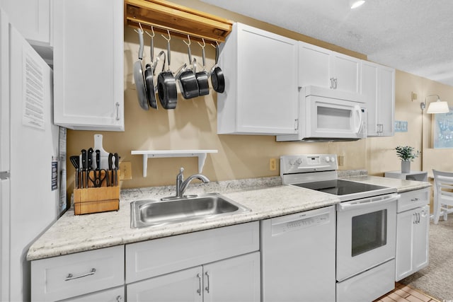 kitchen featuring white appliances, white cabinetry, sink, and a textured ceiling