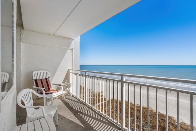 balcony featuring a water view and a beach view