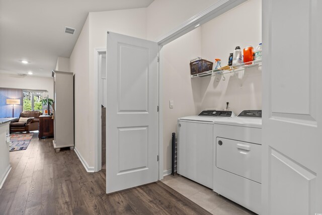 laundry area with laundry area, visible vents, baseboards, light wood-style flooring, and washing machine and clothes dryer