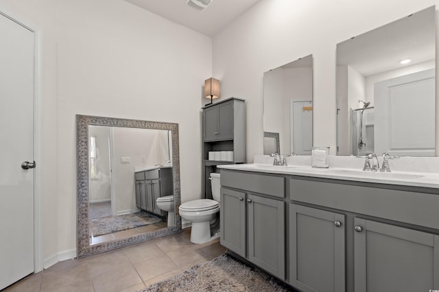 bathroom with double vanity, tile patterned flooring, a sink, and toilet