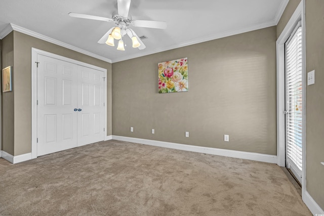 unfurnished bedroom with ceiling fan, a closet, crown molding, and carpet floors