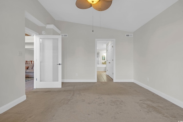 unfurnished bedroom featuring light carpet, vaulted ceiling, ensuite bathroom, and ceiling fan