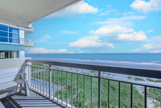 balcony with a water view and a view of the beach