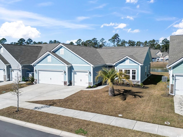 view of front of home with a garage, a water view, central AC, and a front lawn