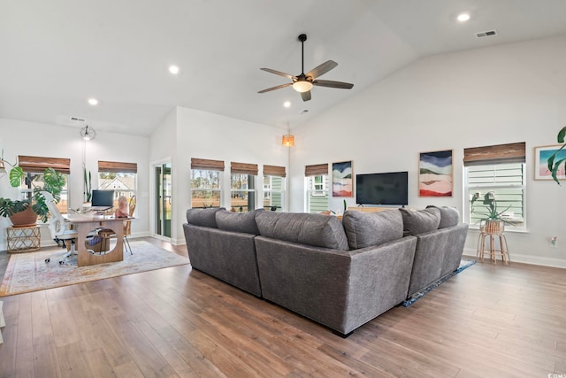 living room with high vaulted ceiling, a wealth of natural light, and light hardwood / wood-style flooring