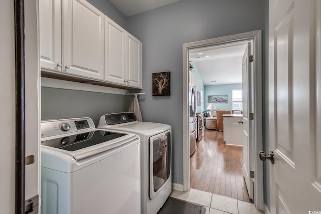 laundry room with washer and dryer, cabinet space, and light tile patterned floors