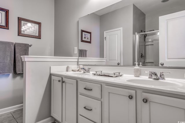 bathroom with double vanity, a shower stall, a sink, and tile patterned floors