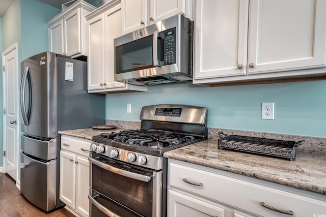 kitchen with appliances with stainless steel finishes, white cabinetry, and light stone counters