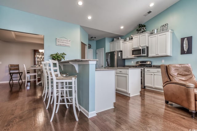 kitchen with visible vents, a kitchen island, white cabinetry, and stainless steel appliances