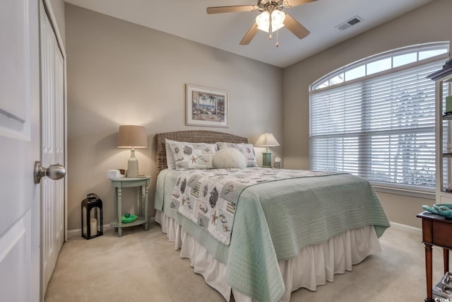 bedroom featuring baseboards, ceiling fan, visible vents, and light colored carpet