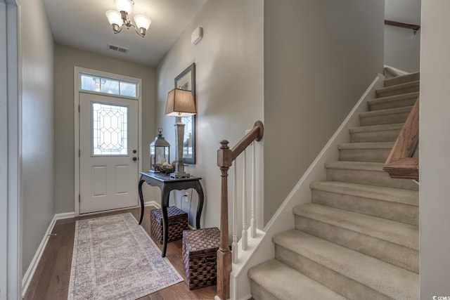 foyer entrance with dark wood-style floors, visible vents, stairway, and baseboards