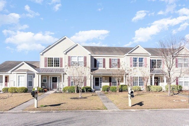 townhome / multi-family property with a front lawn and a standing seam roof