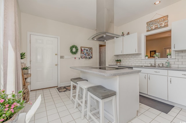 17 Racquet Club Dr, Pawleys Island, SC 29585 - kitchen with island range hood, a sink, tasteful backsplash, light tile patterned flooring, and white cabinetry