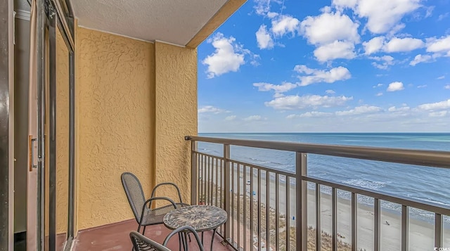 balcony with a water view and a view of the beach