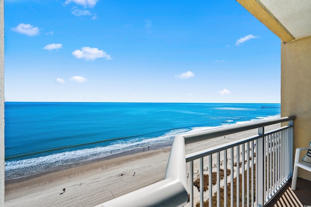 balcony with a water view and a view of the beach