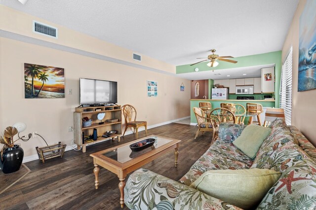 living room featuring ceiling fan and dark wood-type flooring