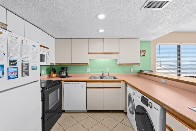 kitchen with sink, white appliances, white cabinets, light tile patterned floors, and washer / dryer