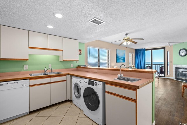 kitchen featuring sink, separate washer and dryer, white dishwasher, kitchen peninsula, and white cabinets