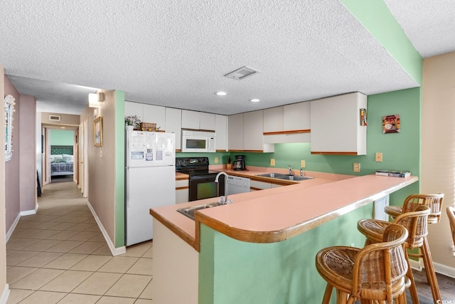 kitchen featuring white appliances, white cabinetry, sink, and kitchen peninsula