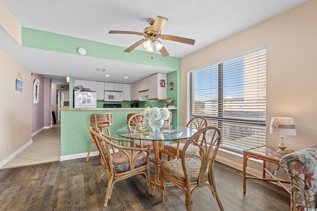 dining space featuring ceiling fan, light hardwood / wood-style flooring, and a textured ceiling