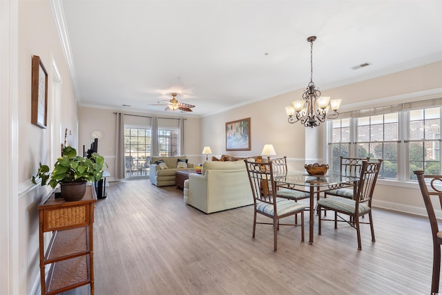 dining area with ceiling fan with notable chandelier, plenty of natural light, crown molding, and light hardwood / wood-style flooring