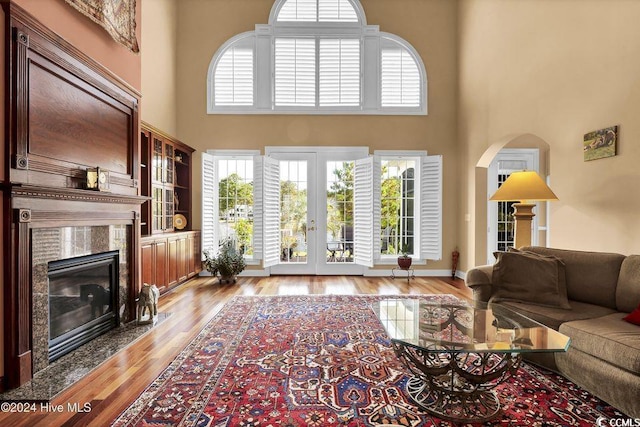 living room featuring light hardwood / wood-style flooring, a premium fireplace, a high ceiling, and a healthy amount of sunlight