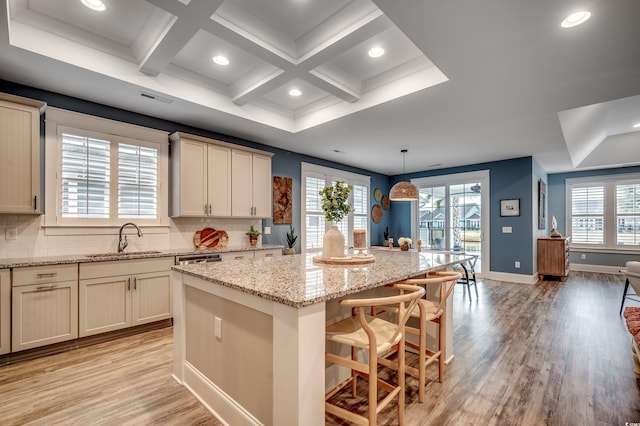 kitchen with cream cabinets, hanging light fixtures, a kitchen island, sink, and a kitchen breakfast bar