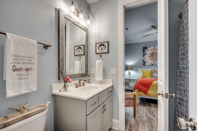 bathroom featuring toilet, vanity, ceiling fan, and wood-type flooring