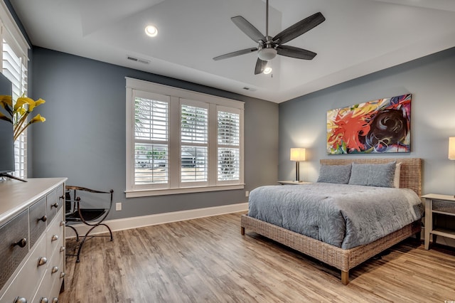 bedroom with a tray ceiling, ceiling fan, and light hardwood / wood-style floors