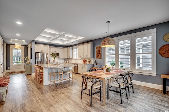 dining area with coffered ceiling, light hardwood / wood-style flooring, and beamed ceiling