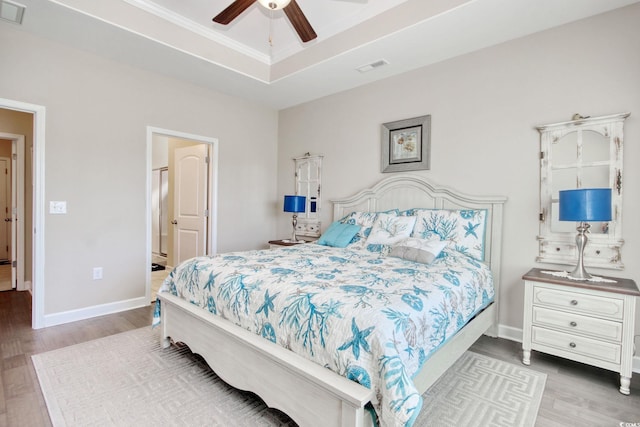 bedroom featuring light hardwood / wood-style flooring, ceiling fan, and a raised ceiling