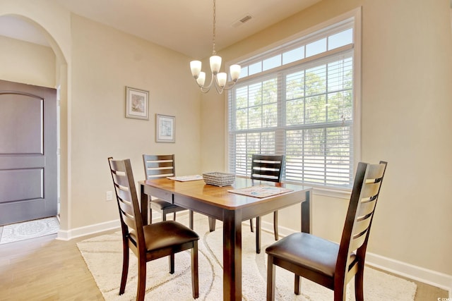 dining room with light wood-type flooring and an inviting chandelier