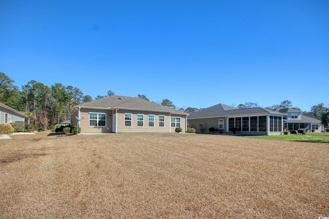 back of house with a lawn and a sunroom