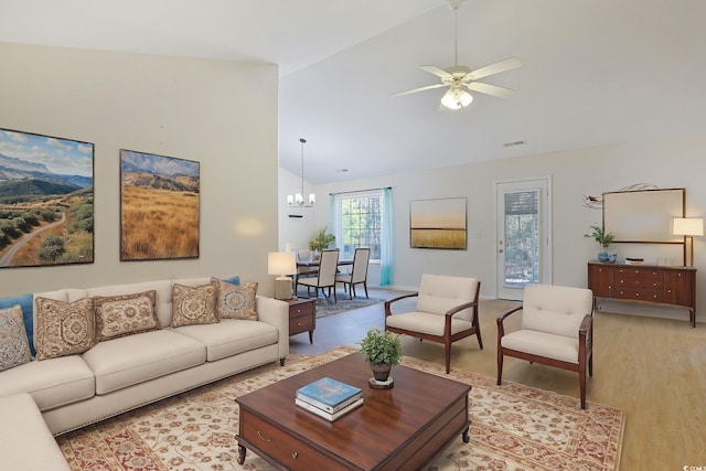 living room with ceiling fan with notable chandelier, high vaulted ceiling, and light hardwood / wood-style floors