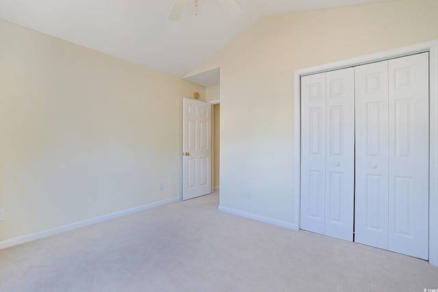 unfurnished bedroom featuring vaulted ceiling, ceiling fan, a closet, and light colored carpet