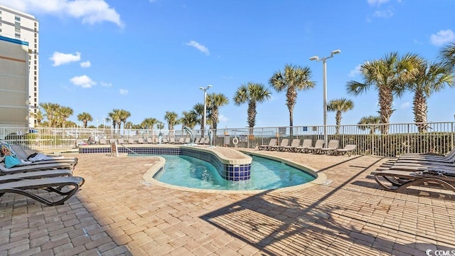 community pool with a patio area and fence