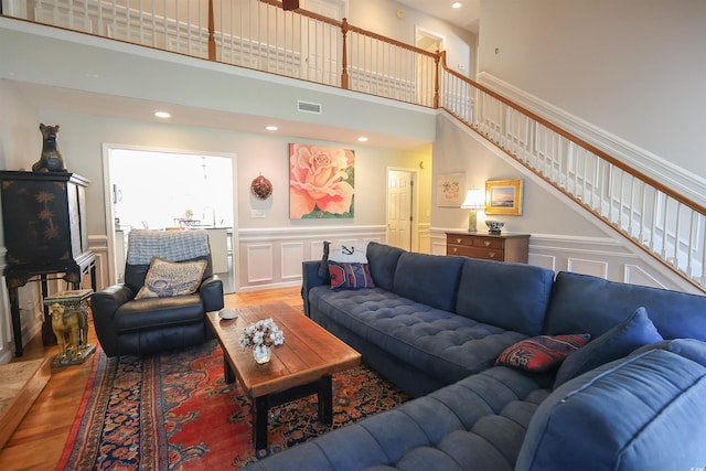 living area with visible vents, a decorative wall, stairway, and wood finished floors