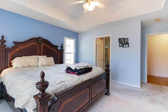 bedroom featuring ceiling fan, a raised ceiling, and light colored carpet