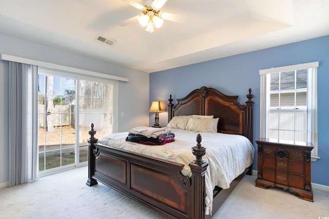 carpeted bedroom with a tray ceiling, access to outside, and ceiling fan