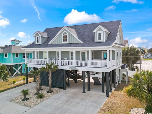 raised beach house with covered porch, a shingled roof, a carport, and concrete driveway